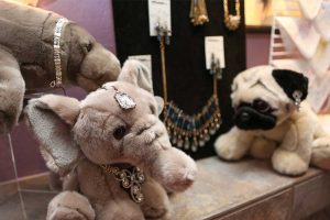 The jewelry section at Andrea's Red Dress featuring a felt board with earrings and large stone necklaces and plush animals donning bracelets, earrings and necklaces.